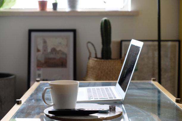 把咖啡杯放在桌上。模糊笔记本电脑和家居装饰。在家工作的概念图片下载
