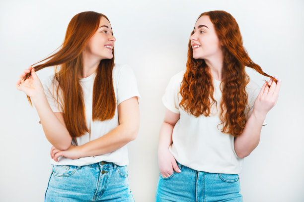 两个红头发的年轻女子站在孤立的白色背景上，抚摸着她们美丽的长发，风格和美的概念图片下载