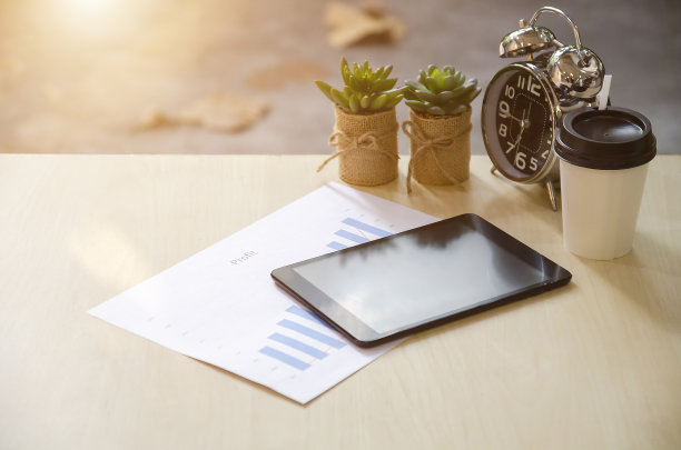 办公室办公桌背景与空白平板，时钟，报告纸，笔记本电脑笔记本电脑，仙人掌植物和一杯咖啡在早晨和阳光与标签文本横幅广告的拷贝空间。图片下载