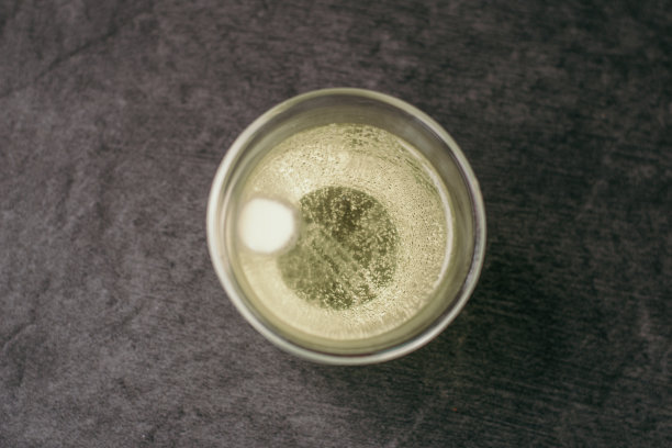 在灰色的石头背景上的玻璃高脚杯里的冒泡的维生素c片。预防流感及感冒，增强人体对病毒的免疫力图片下载