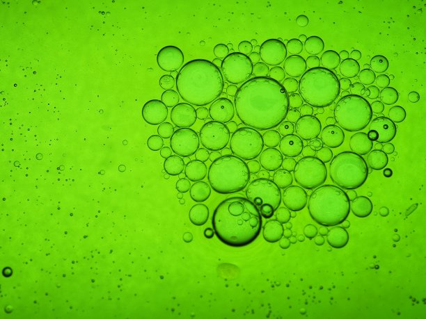 混合水和油，美丽的颜色。绿色的光。特写镜头。抽象的宏观背景。水和油会起泡。摘要光照明图片下载