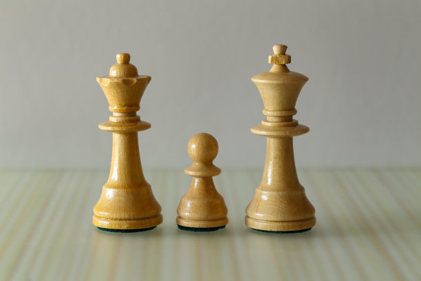 家庭-白王后，国王和卒-棋子在一个模糊的棕色背景图片下载