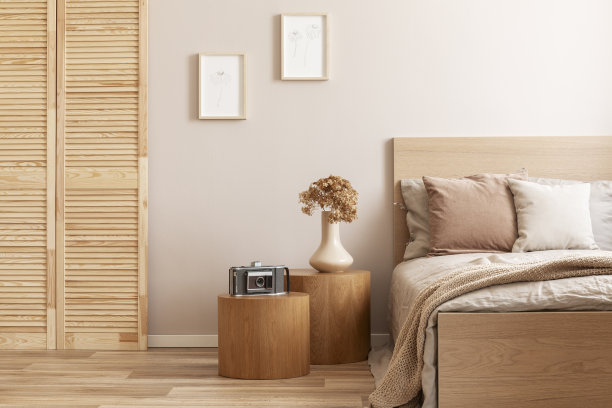 老式相机放在舒适的单人床旁边的圆形木质床头柜上图片下载