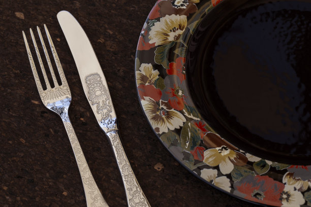 俯视图的一个空的黑色圆形盘子上面画着花的棕色深色软木底座。图片下载