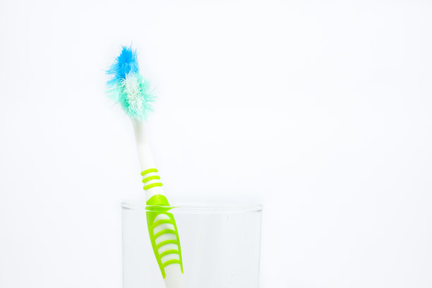 用透明玻璃清洁牙齿的旧牙刷(损坏的)被隔离在白色的背景上-概念“你应该多久换一次牙刷?”图片下载