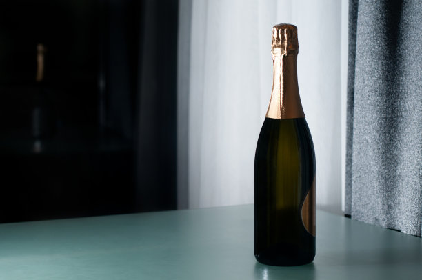 优雅的香槟酒瓶放在玻璃桌上。酒、酒、广告和假日概念。图片下载