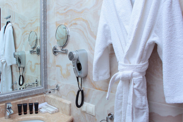 酒店浴室里挂着一件白色的毛巾布长袍。照片在室内。空间的副本图片下载