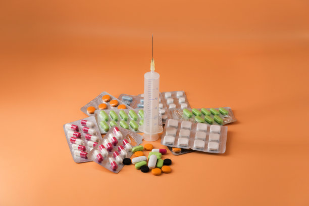 照片中央橙色的背景上放着一张载着不同药丸和注射器的幻灯片。图片下载