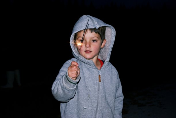 一个小孩在烟花之夜持有一个烟花图片下载