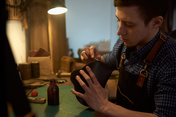 大师在他的工作室为未来的产品绘制皮革图案的边缘。图片下载