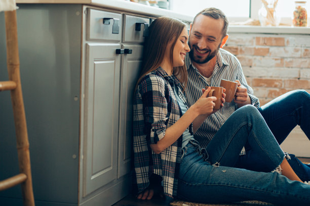 欢乐的年轻夫妇在厨房地板上喝茶的照片图片下载