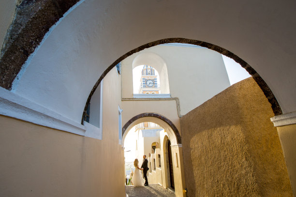 美丽的新婚夫妇走在圣托里尼的老街上图片下载