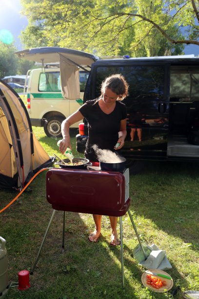 一个女人在山中营地的烤架上做饭图片下载
