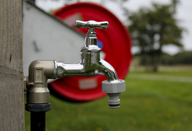 在乡村小屋的院子里用软管喷嘴泵水。图片下载