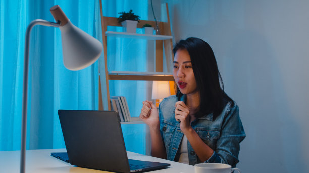 聪明的自由职业女性在使用笔记本电脑后听音乐，晚上在家的客厅工作。图片下载