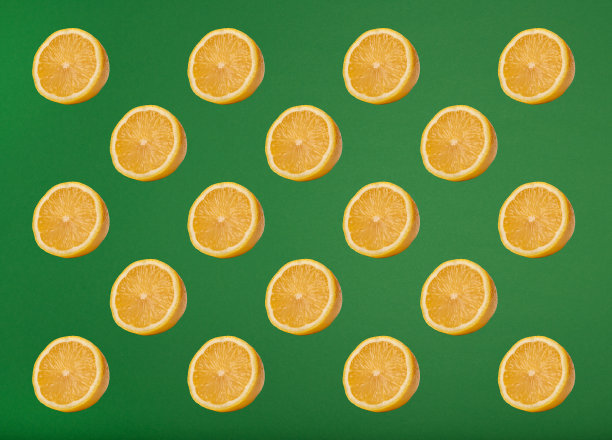 时髦的夏季模式与黄色柠檬片在明亮的绿色背景。最小的夏天的概念。图片下载