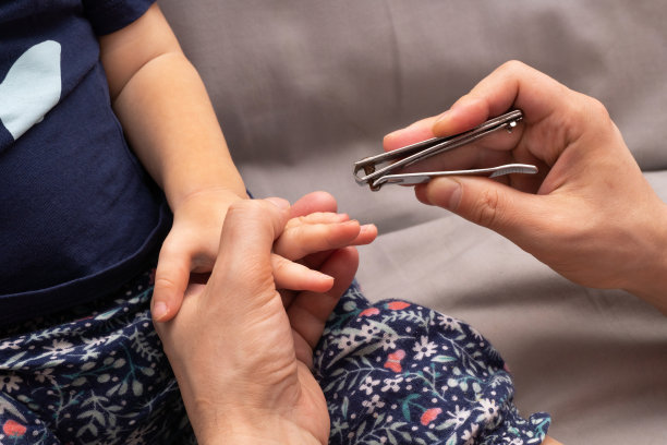 父亲给他的孩子修指甲。关闭的过程，修剪指甲与剪刀。图片下载