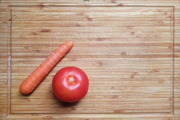 一个带有番茄和胡萝卜的木板的俯视图。作为食谱网站或烹饪博客的背景模板很有用。烹饪的纹理和配料。图片下载