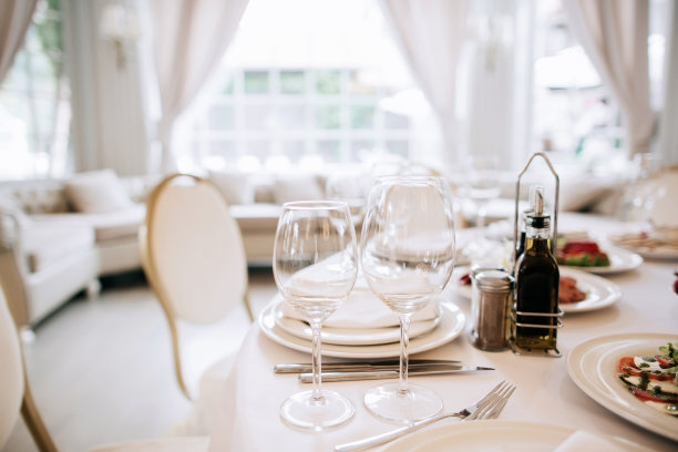 典雅的白色餐具。餐厅用盘子和玻璃杯招待的桌子图片下载