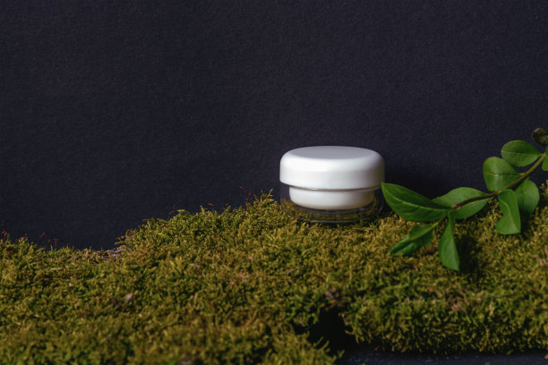 润肤霜瓶在黑色背景与苔藓和绿色植物。天然有机化妆品概念图片下载