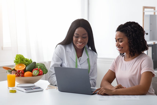 微笑的女医生和病人使用笔记本电脑在诊所图片下载