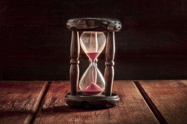 时间的概念。一个沙漏，在一个黑色的乡村木制背景上，有一个文字的地方图片下载