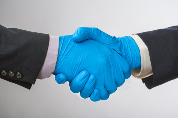 两个戴着乳胶手套握手的商人图片下载