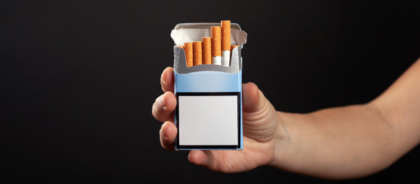 手里拿着一包香烟，背景是黑色的。香烟广告图片下载