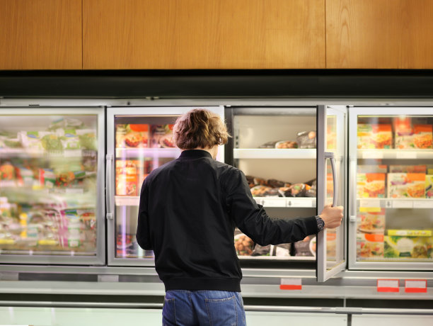 从超市冰箱里挑选冷冻食品的人图片下载