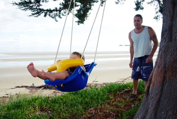 父亲在沙滩上推着蹒跚学步的孩子图片下载