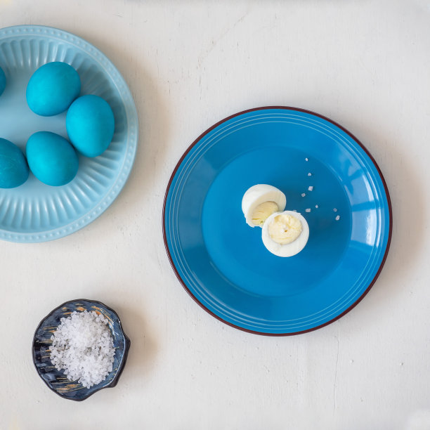 白色木桌上的两个蓝色陶瓷盘子上放着复活节的蓝蛋图片下载