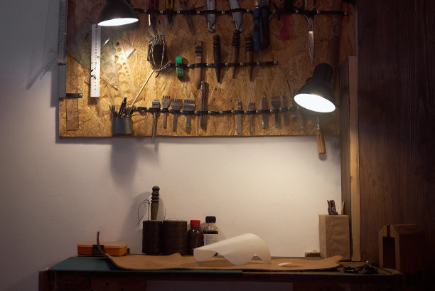 手工制作皮革制品的工具放在木桌上。一套皮革工作的工艺工具，在皮匠的工作桌上。图片下载