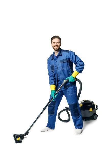 年轻英俊的男子与胡子在蓝色工作制服清洁房间微笑和吸尘孤立在白色的背景。图片下载