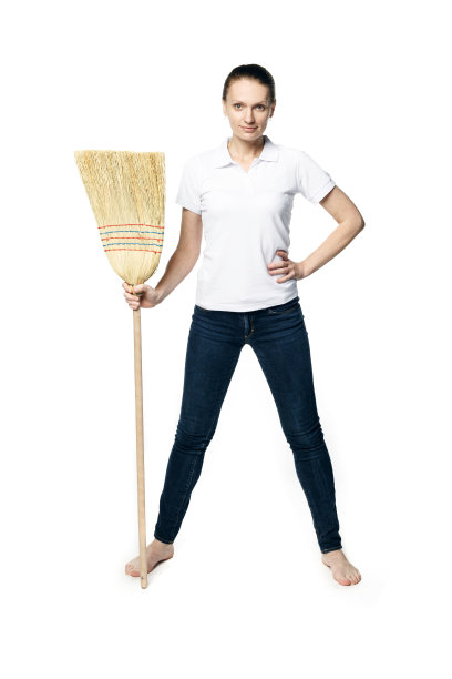 美丽的女人在一个白色t恤摆姿势拿着扫帚在她的手孤立在一个白色的背景，像一个家庭主妇图片下载