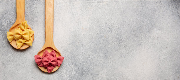 生的彩色意大利面在木制勺子上的混凝土背景。副本的空间。从上面看。图片下载