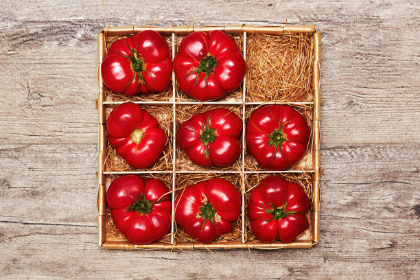顶视图的木箱与成熟的西红柿和稻草在底部。木制背景。收获和蔬菜图片下载