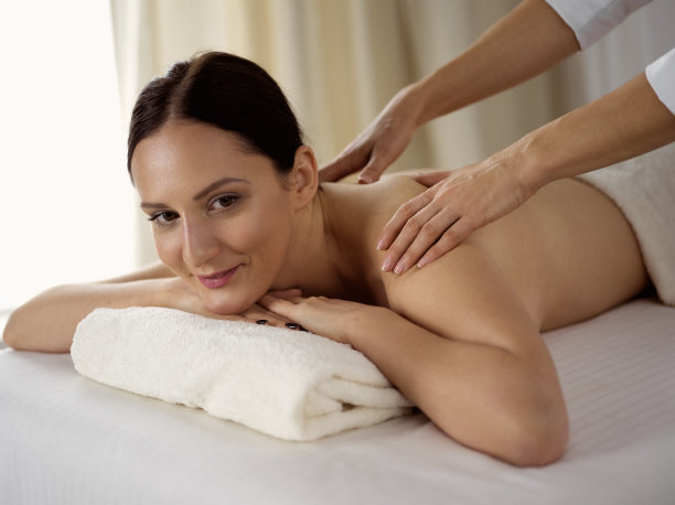 漂亮的黑发女子享受水疗沙龙的背部按摩程序。美丽的概念图片下载