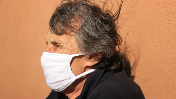 祖母或老年妇女戴着口罩在阳台上抗击COVID-19图片下载