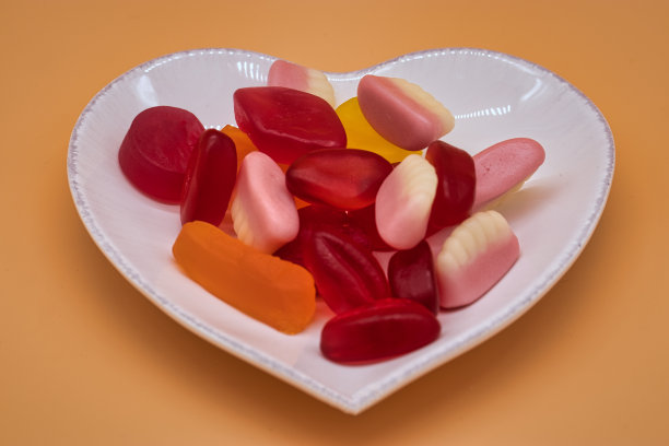 彩色心形糖果孤立在橙色背景图片下载