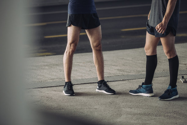 城市跑步者:两个穿着运动服的人站在街上图片下载