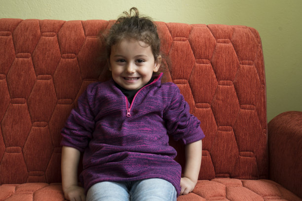 可爱的小女孩坐在沙发上，室内写真图片下载