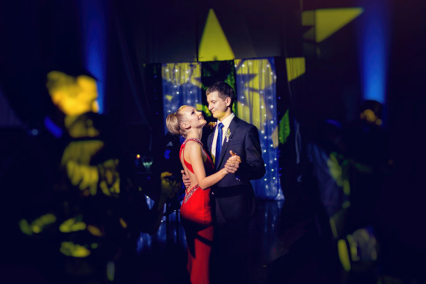 时尚奢华的新娘穿着红色礼服，新郎在餐厅跳舞，庆祝婚礼图片下载