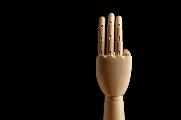人体模型的木制手在黑色背景上显示出三根手指。学会数——三。图片下载
