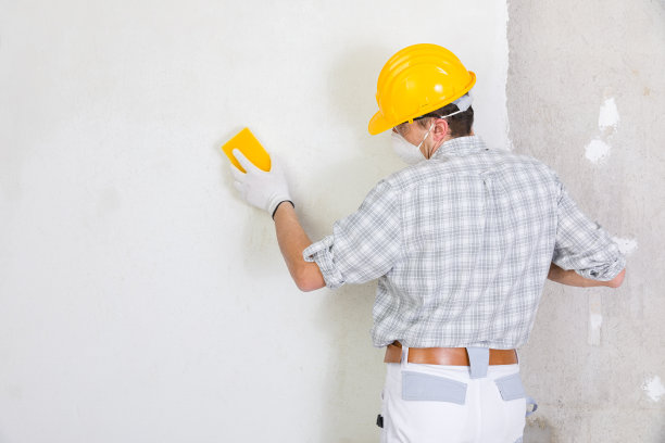 建筑工打磨和光滑新抹灰的墙壁图片下载