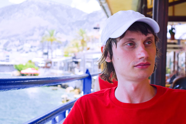 一个年轻人正坐在海边的咖啡馆里。图片下载