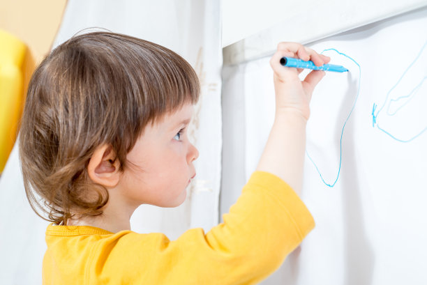 小孩用毛笔在白板上画画。自我隔离的家庭活动图片下载