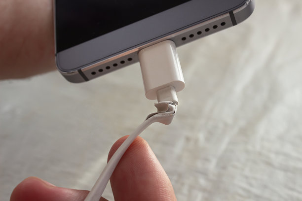 一根破旧的电线连接着你的智能手机。一个男人拿着一个电话，他的手里有一根撕破的电线。图片下载