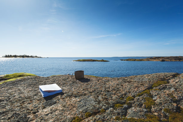 在海边的石头上放着一本书。图片下载