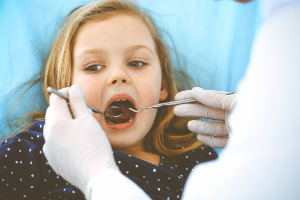小女孩张大嘴巴坐在牙科椅上接受医生的口腔检查。拜访牙医的办公室。医学概念。健美的照片图片下载