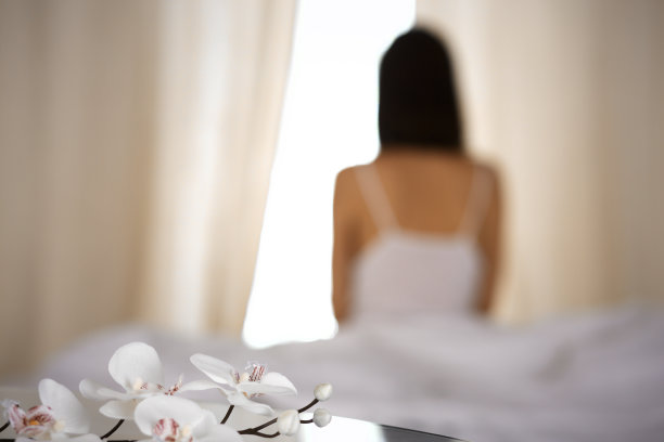 女人在床上伸开双手醒来后，太阳耀斑。深色头发的女人进入一个愉快和放松的一天后，睡了一个好觉和后视图。崭新的一天和快乐的周末图片下载